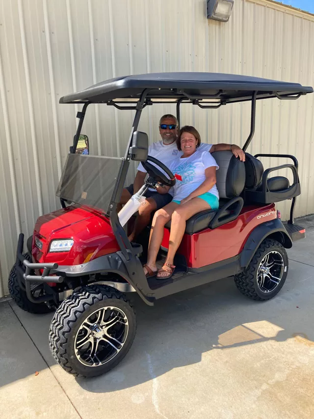 smiling couple on golf cart