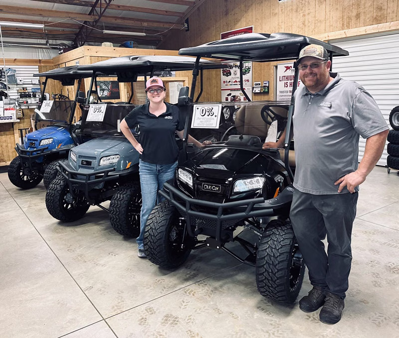 Owners of Allison Golf Cars, Casey and Stephanie, standing beside a golf car smiling at camera