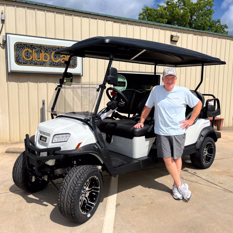 Customer standing beside his golf cart smiling